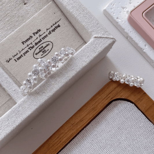 Pearl hair accessories on a wooden surface with a textured box in the background.