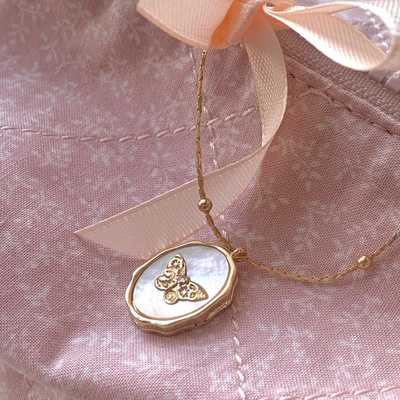 Heart-shaped locket with gold chain on a pink fabric background