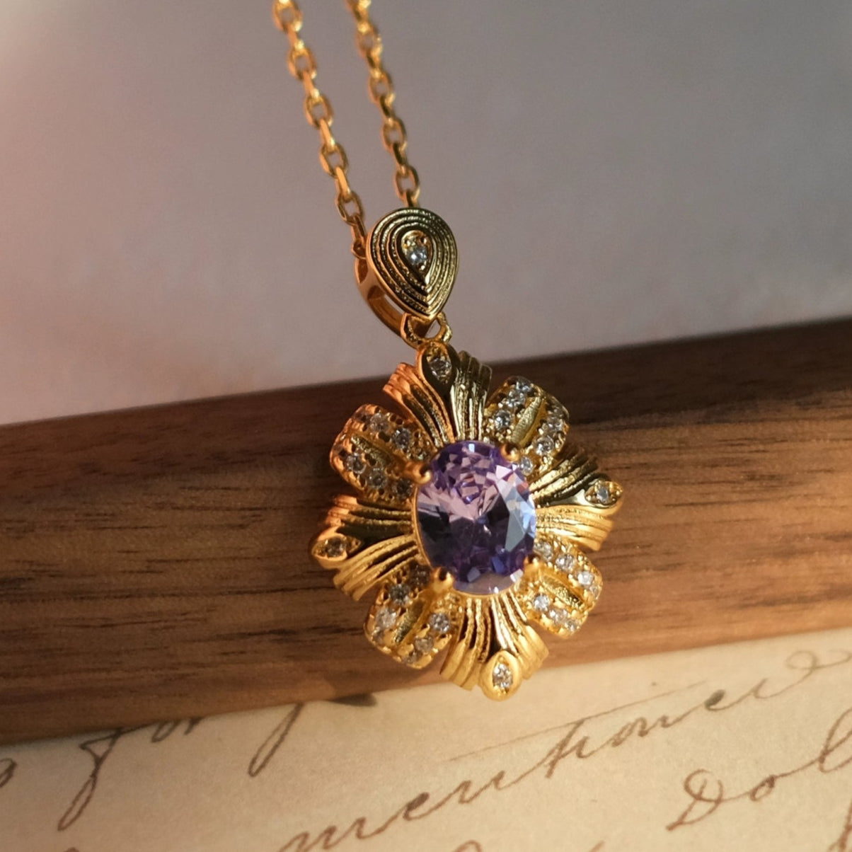 Gold necklace with a purple gemstone pendant on a wooden surface, branded 'SW accessories'.