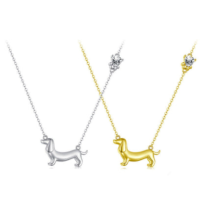 Two dog-shaped pendants, one in silver and one in gold, on white backgrounds.