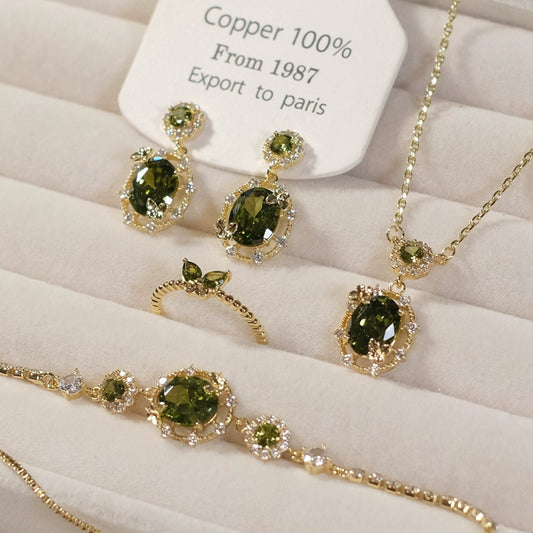 Jewelry set with green gemstones on a white cushion, branded 'SW accessories'.