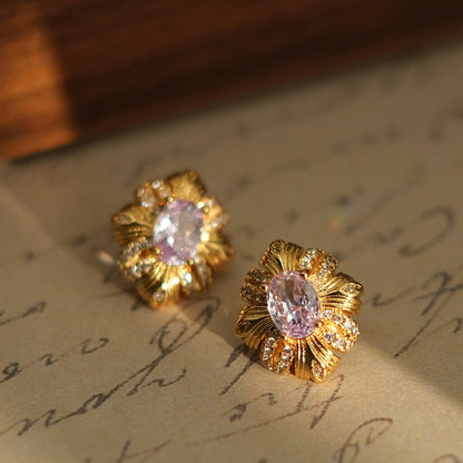 Gold earrings with pink gemstones on a vintage letter background, branded 'SW accessories'.