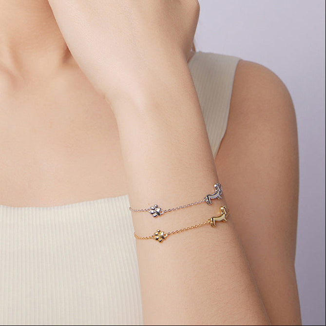 Woman wearing two gold bracelets on a plain background