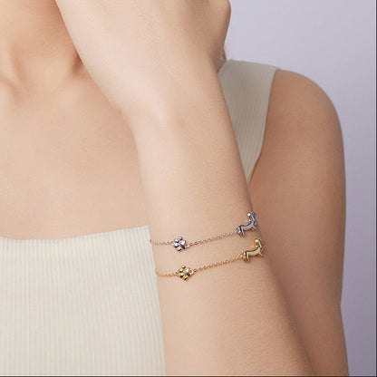 Woman wearing two gold bracelets on a plain background