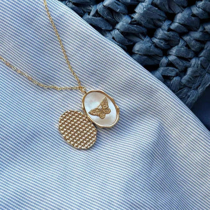 Gold necklace with a butterfly pendant on a textured blue and white fabric background